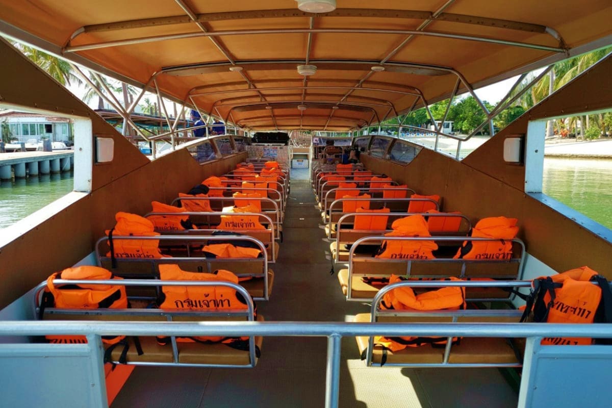 Koh Samui to Surat Thani Ferry Transfers Interior of orange and black passenger ferry boat with rows of seats and canvas canopy roof, docked at waterside terminal