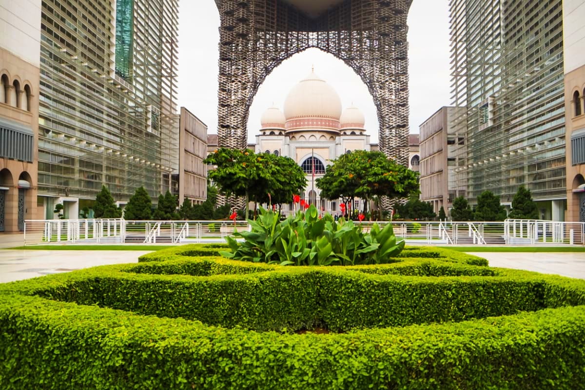 Kuala Lumpur City Discovery Tour Masjid Negara mosque with pink domes framed by modern skyscrapers and green garden courtyard in Kuala Lumpur