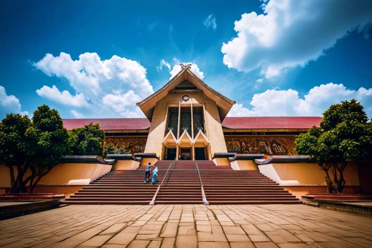 Modern architectural building with steep peaked roof and wide staircase entrance under blue sky with white clouds in Kuala Lu