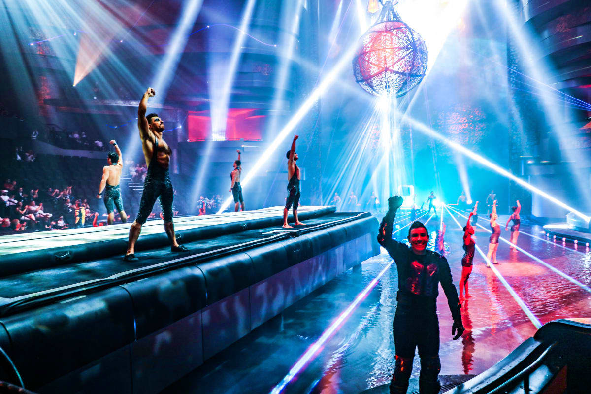 La Perle by Dragone Dubai Acrobatic performers on illuminated platforms during La Perle by Dragone Dubai show with dramatic blue and pink stage lightin