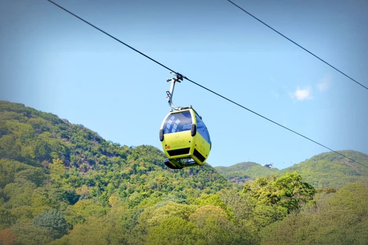 Langkawi Cable Car Yellow and blue cable car suspended above forested mountains in Langkawi, Malaysia against clear blue sky