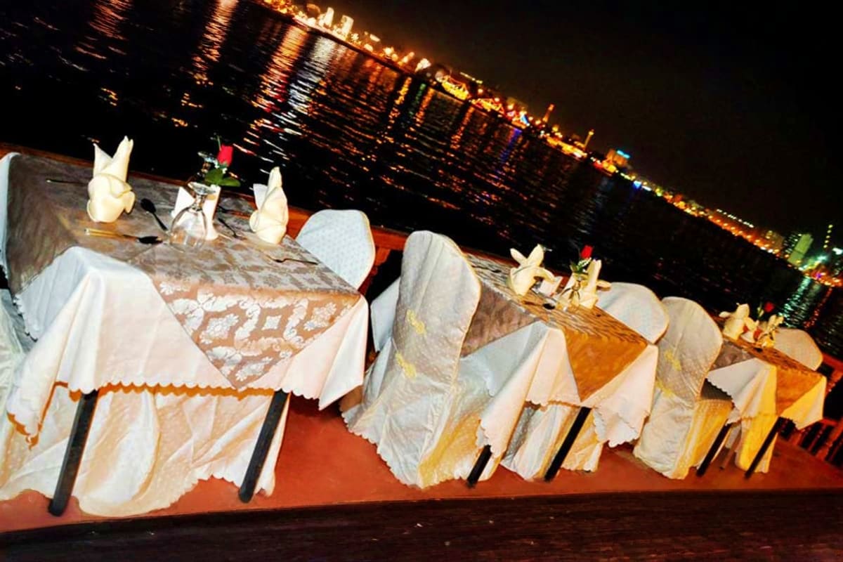 Elegant waterfront dining setup on Dubai Marina with white chair covers, formal place settings, and illuminated cityscape at 
