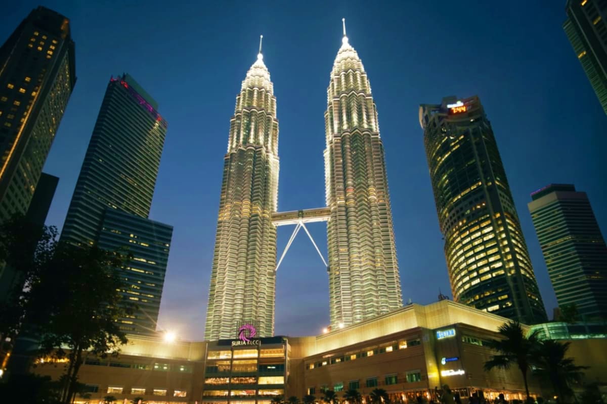 Petronas Twin Towers Kuala Lumpur Petronas Twin Towers illuminated at night in Kuala Lumpur skyline with surrounding skyscrapers and shopping mall below