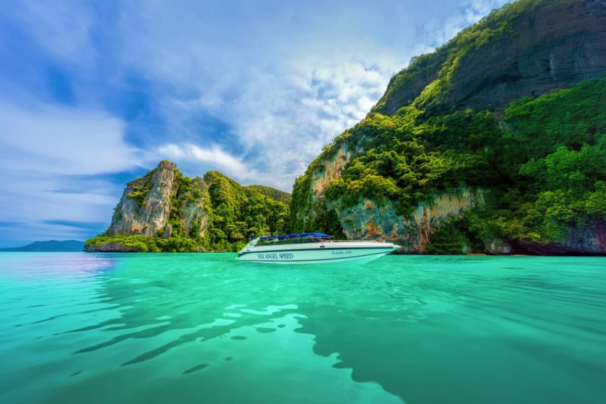 Phi Phi Island Bamboo Island Maya Bay and Pileh Lagoon by Speed Boat Speed boat anchored in turquoise waters between limestone cliffs covered in lush green vegetation in Thailand