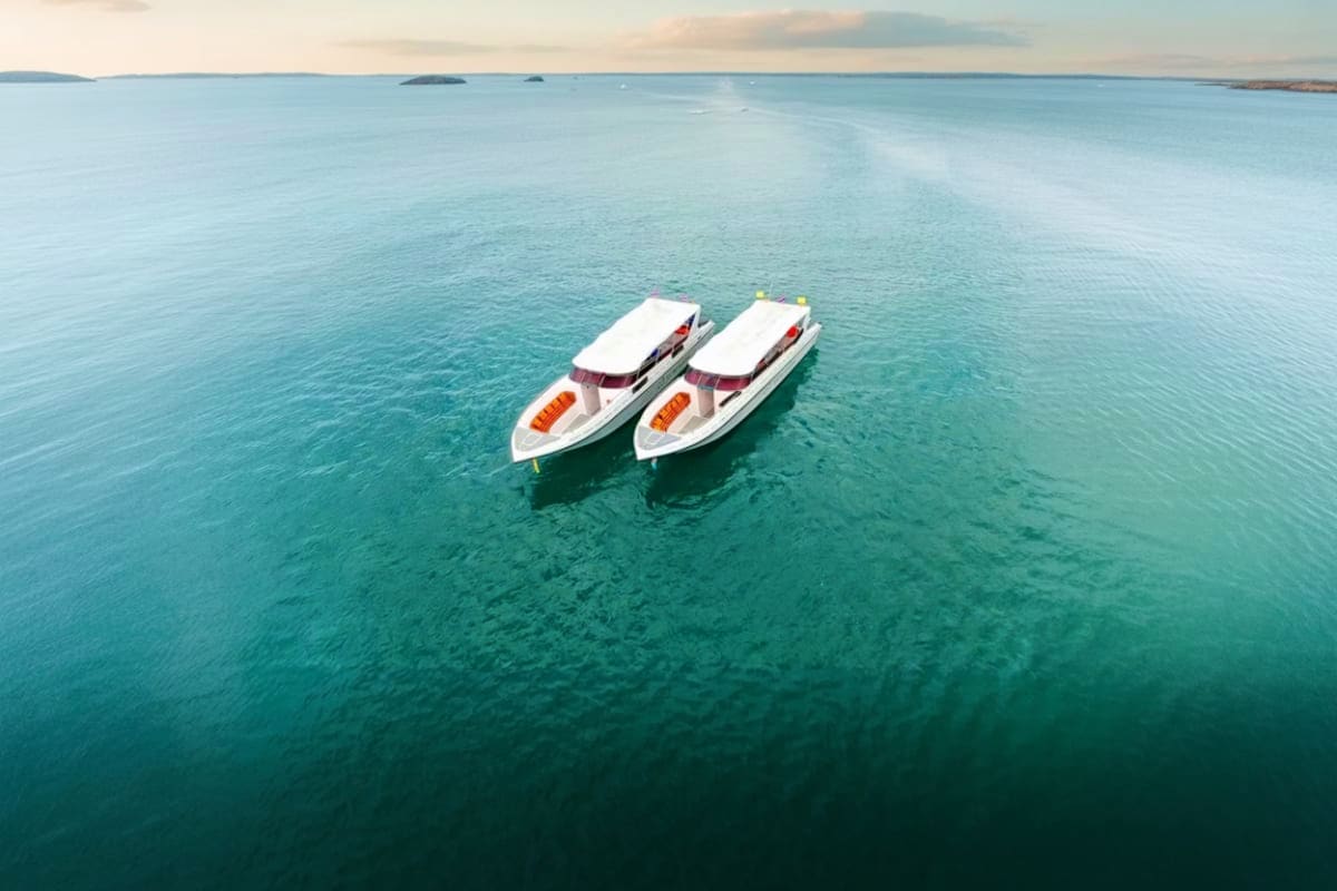 Phi Phi Island Bamboo Island Maya Bay and Pileh Lagoon by Speed Boat Two white speedboats anchored in turquoise water with distant islands and coastline visible under a cloudy sky