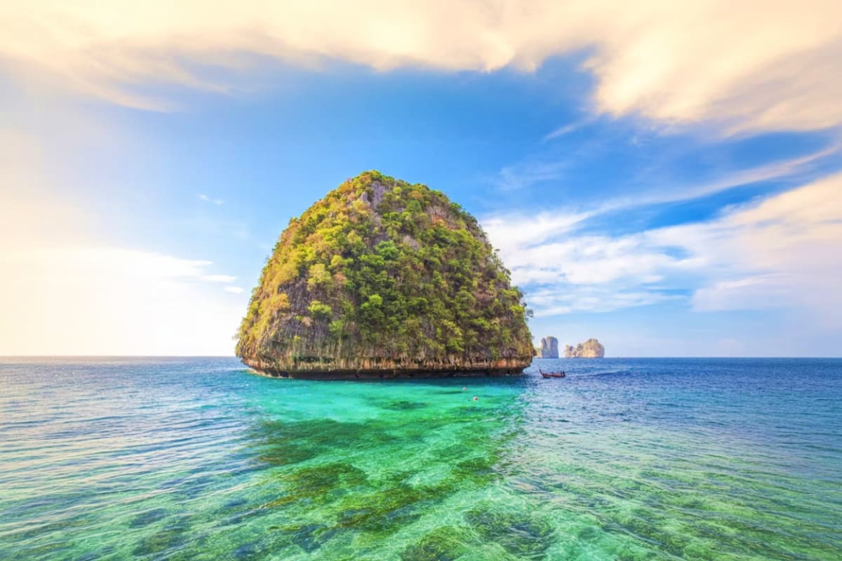 Phi Phi Island Bamboo Island Maya Bay and Pileh Lagoon by Speed Boat Lush forested island with turquoise waters and limestone cliffs in Phi Phi Islands, Thailand, with speedboat visible in dista