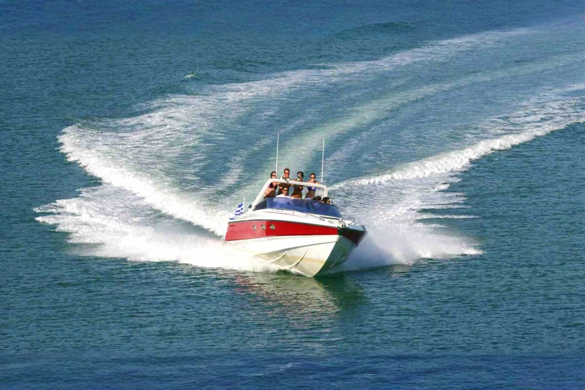 Red and white speedboat with passengers riding through ocean waves near Phi Phi Island, Thailand