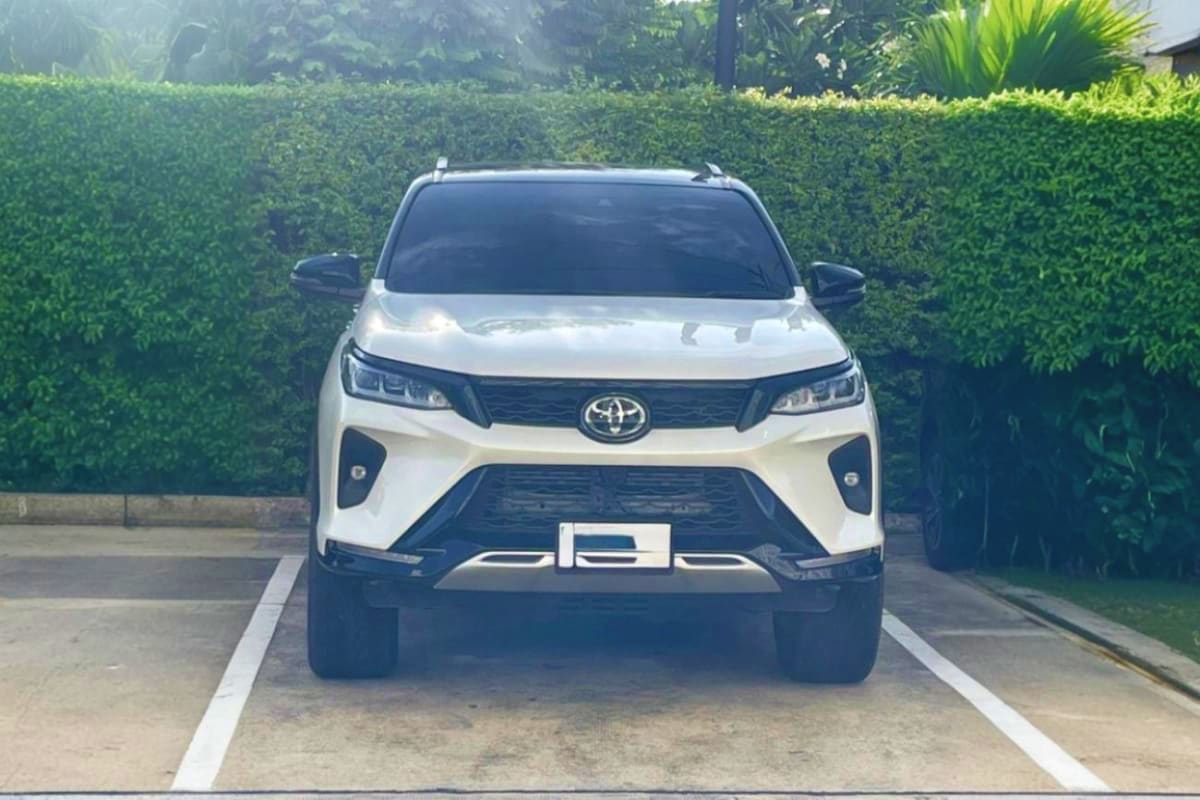 Phuket Airport Pickup White Toyota SUV parked in driveway with green hedge background, representing airport transportation service