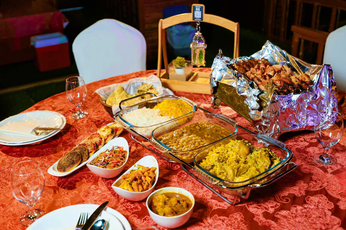 Indian restaurant table with buffet spread including rice, curries, bread, and meat dishes on red tablecloth with place setti