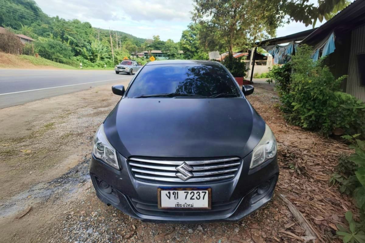Private Vehicle Disposal for Koh Samui Black Suzuki sedan parked on gravel roadside near mountains and rural buildings in Koh Samui Thailand