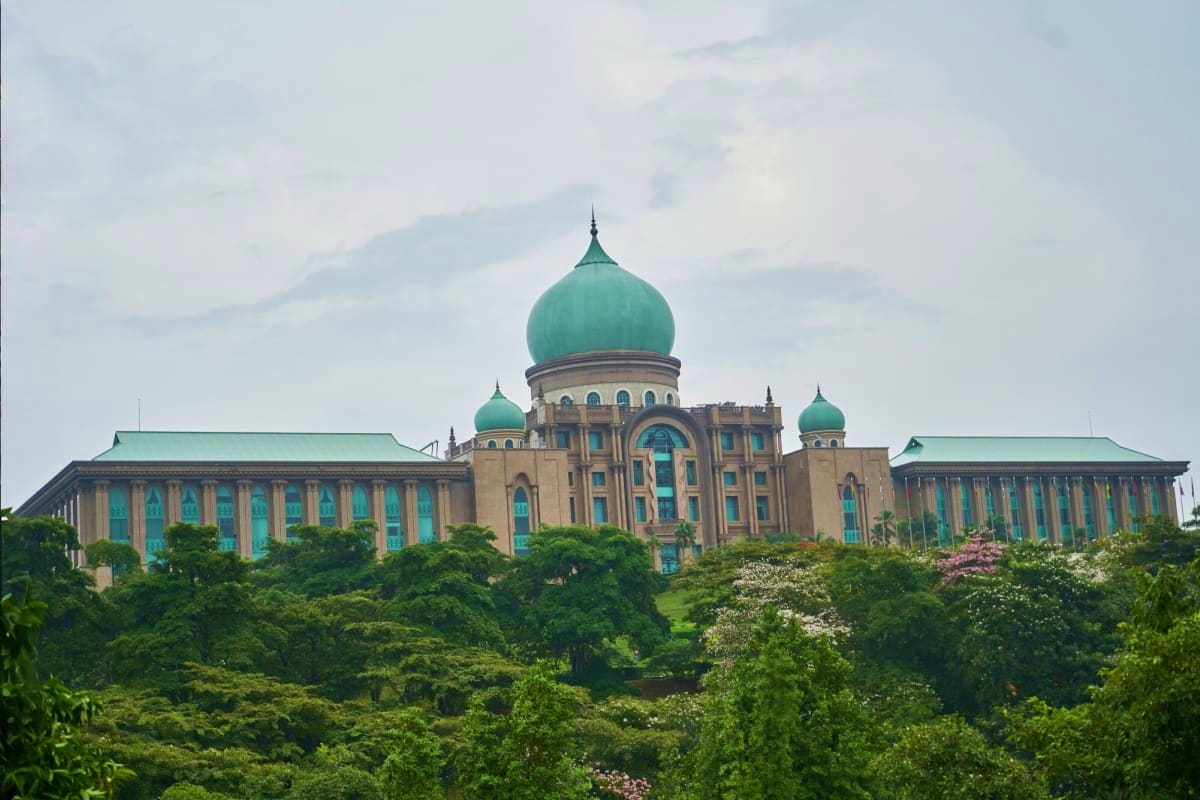 Putrajaya's distinctive government building with green copper domes surrounded by lush tropical vegetation and landscaped gro