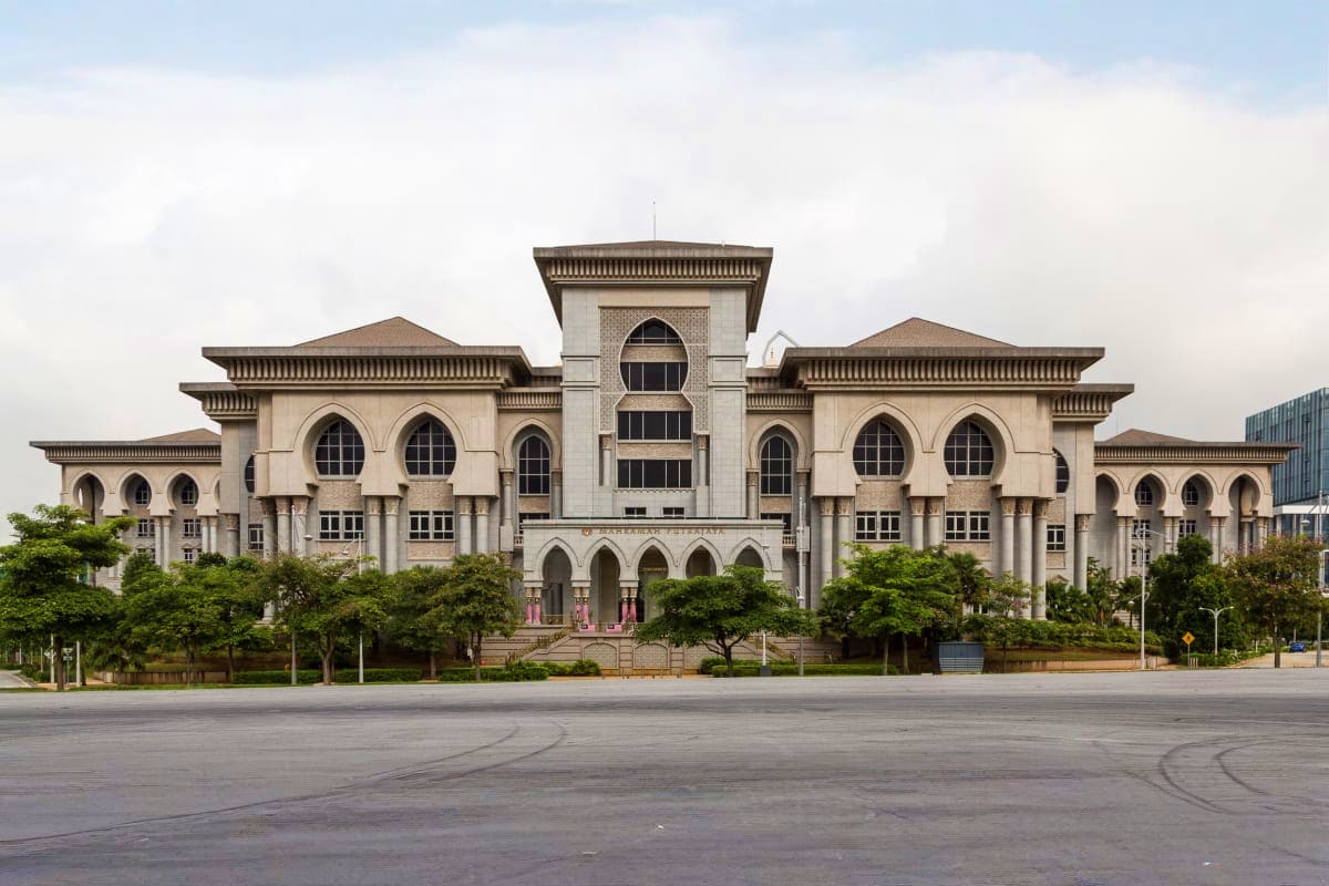 Majestic white neoclassical government building in Putrajaya with symmetrical architecture, domed tower, and landscaped garde