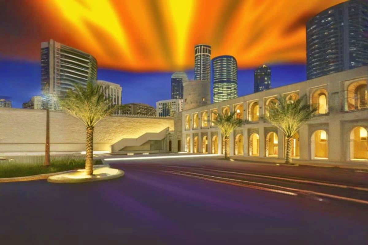 Qasr Al Hosn fortress illuminated at dusk with Dubai skyline and palm trees in the background