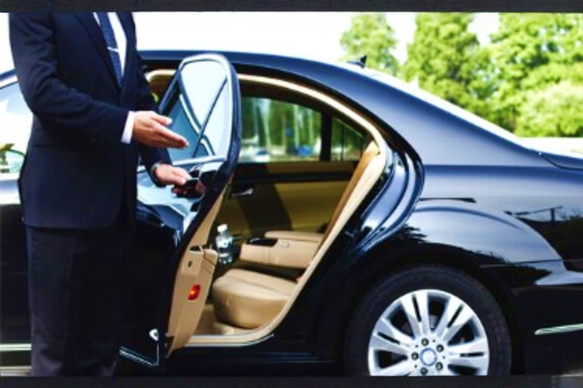 Ramadan Transfer Madina Hotel to Makkah Hotel Businessman in dark suit standing beside open door of black luxury car with beige interior