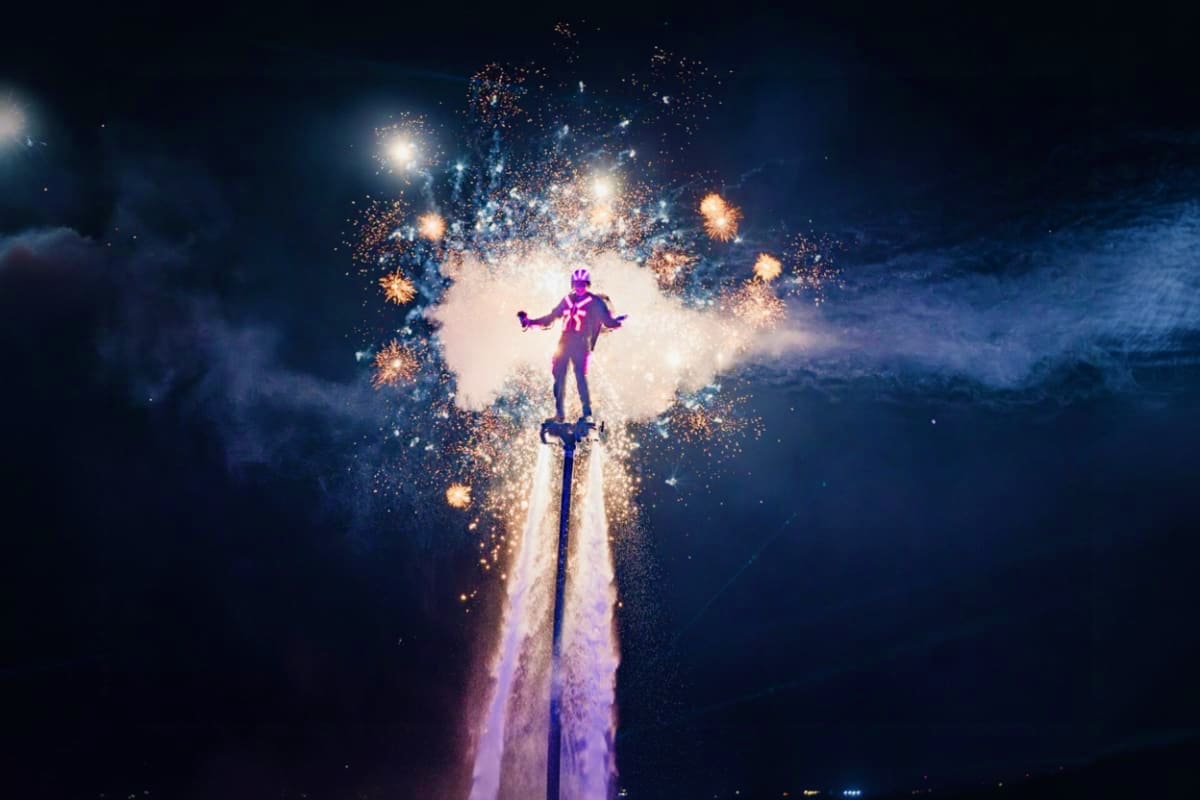 Figure in purple costume standing on tall illuminated pillar surrounded by golden fireworks and sparkling light effects again