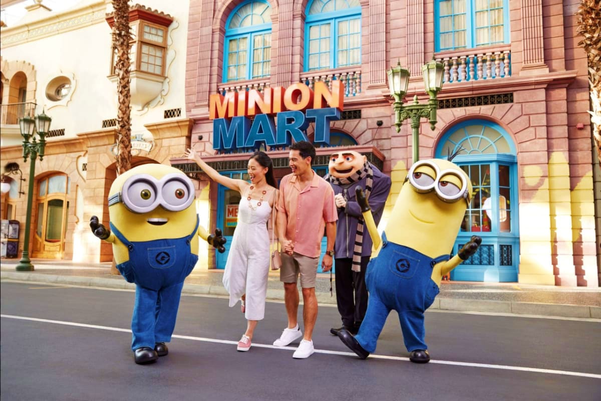 Visitors posing with two Minion characters in front of Minion Mart store at Universal Studios Singapore theme park