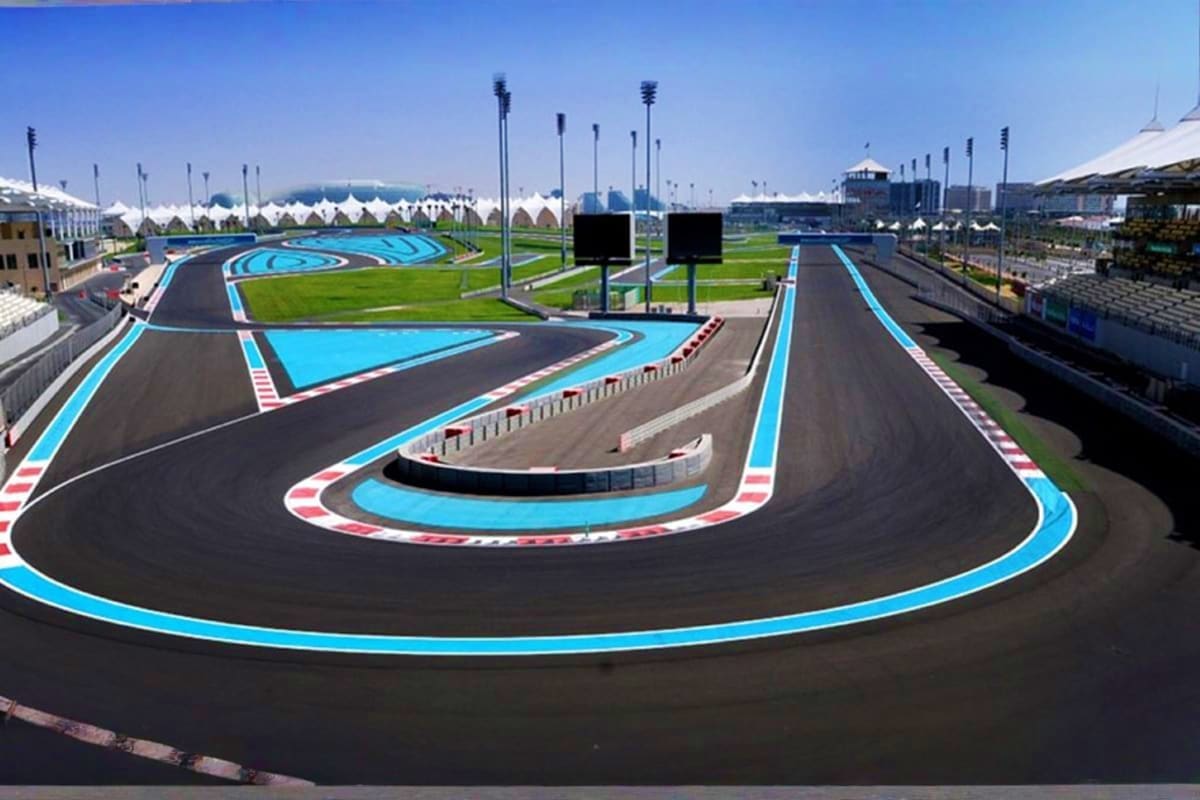Yas Marina Circuit Tour Aerial view of Yas Marina Circuit race track with blue and white lane markings, grandstands, and white tent structures under