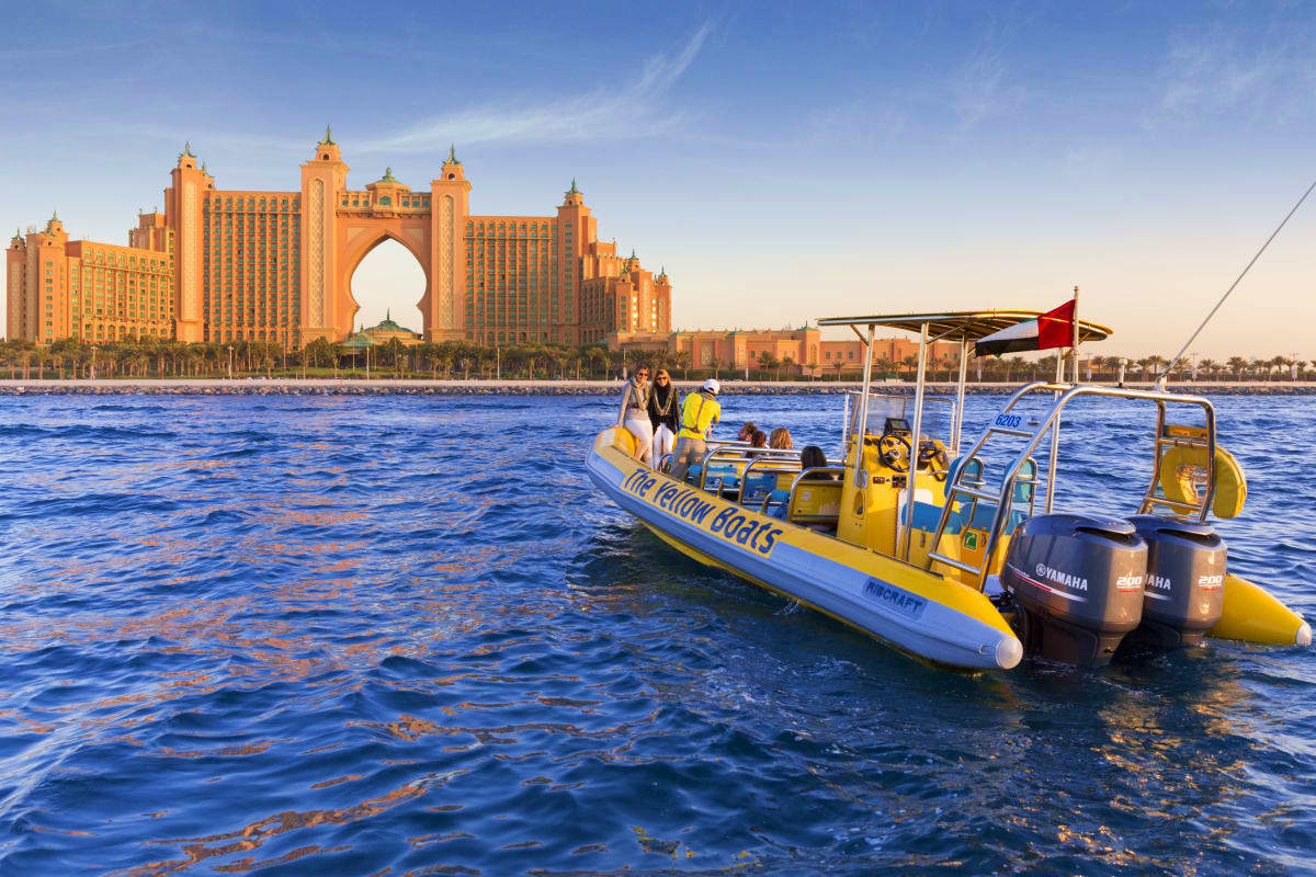 Yellow Boats Dubai Yellow speedboat tour with passengers near Atlantis The Palm hotel in Dubai waters under blue sky