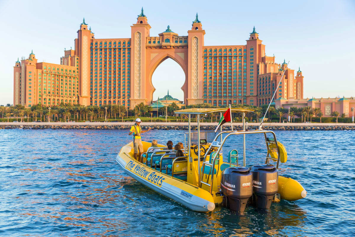 Yellow speedboat with passengers in Dubai waters with Atlantis The Palm hotel in background