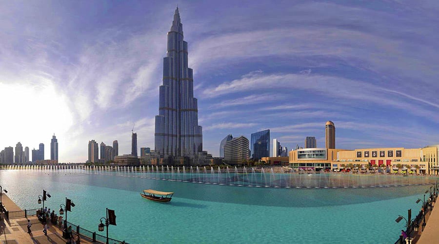 Dubai Fountain Show Lake ride from Ras Al Khaimah Burj Khalifa and Dubai skyline viewed from turquoise fountain lake with traditional wooden boat and promenade in foreground