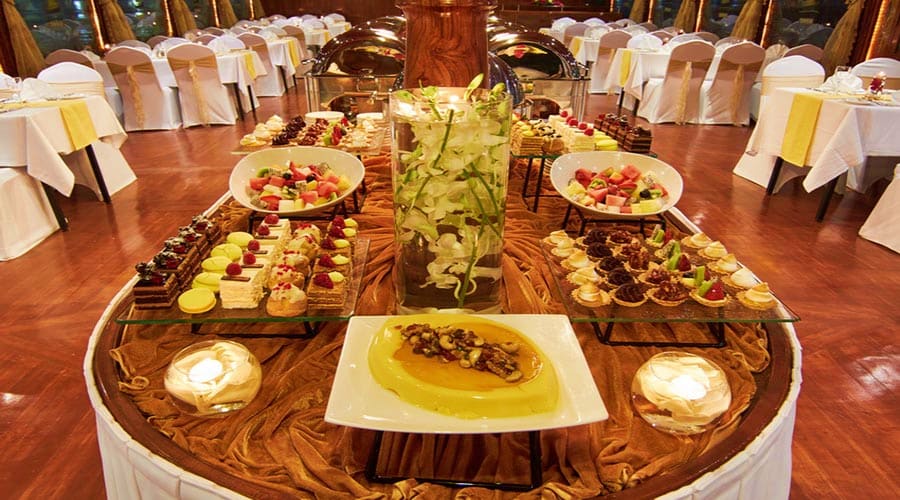 Elegant Iftar buffet setup at Dubai Creek with appetizers, desserts, and floral centerpiece on wooden table with decorated ch