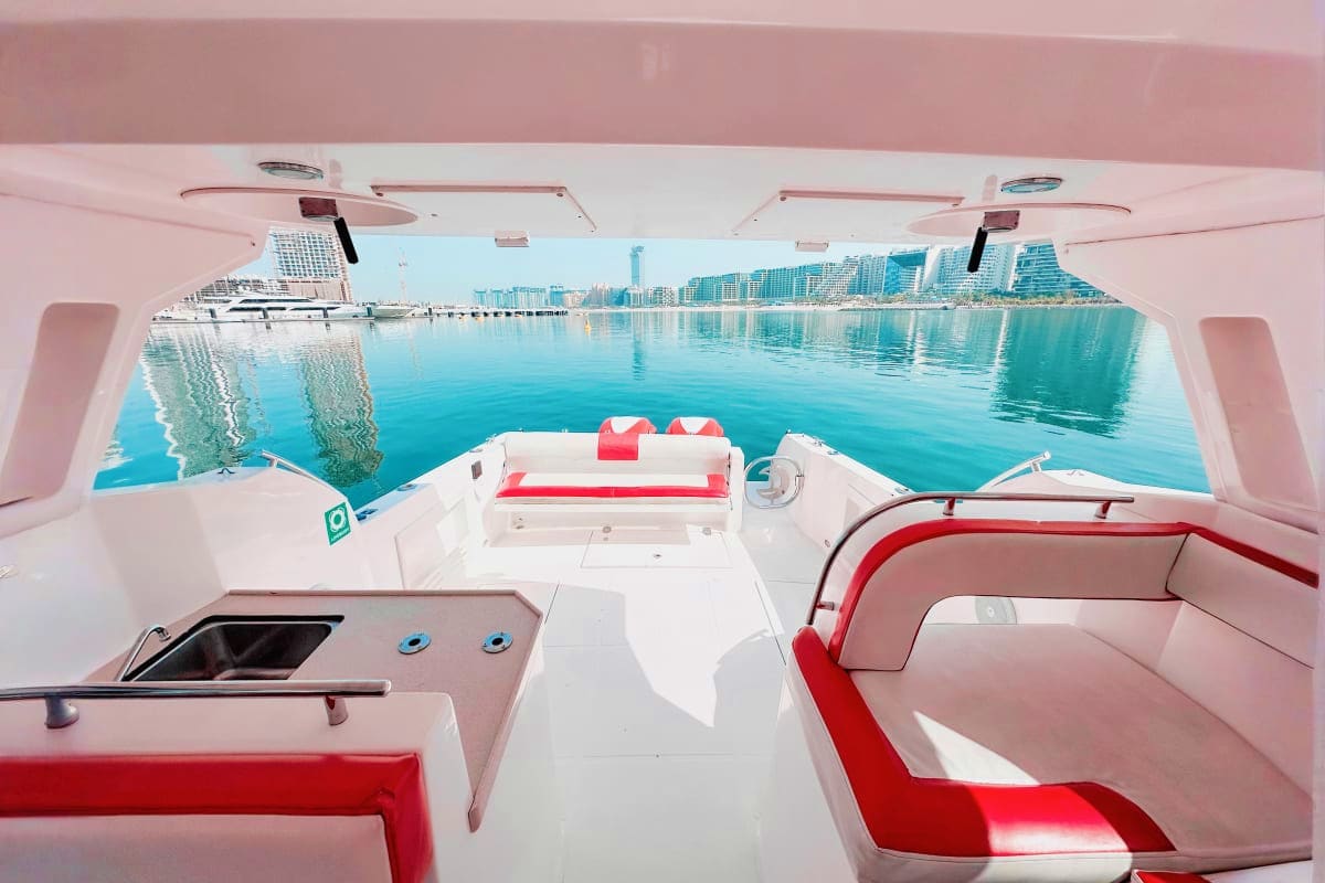 Interior view of Silver Craft X5 yacht with red and white seating, looking out to turquoise water and coastal cityscape with 