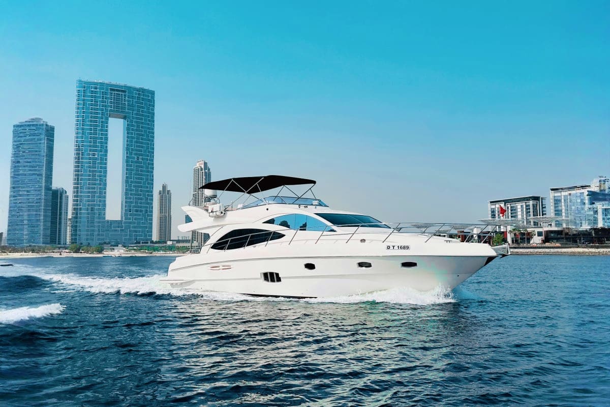 Majesty X3 Luxury white motor yacht with extended canopy anchored in coastal waters near modern high-rise buildings and beach
