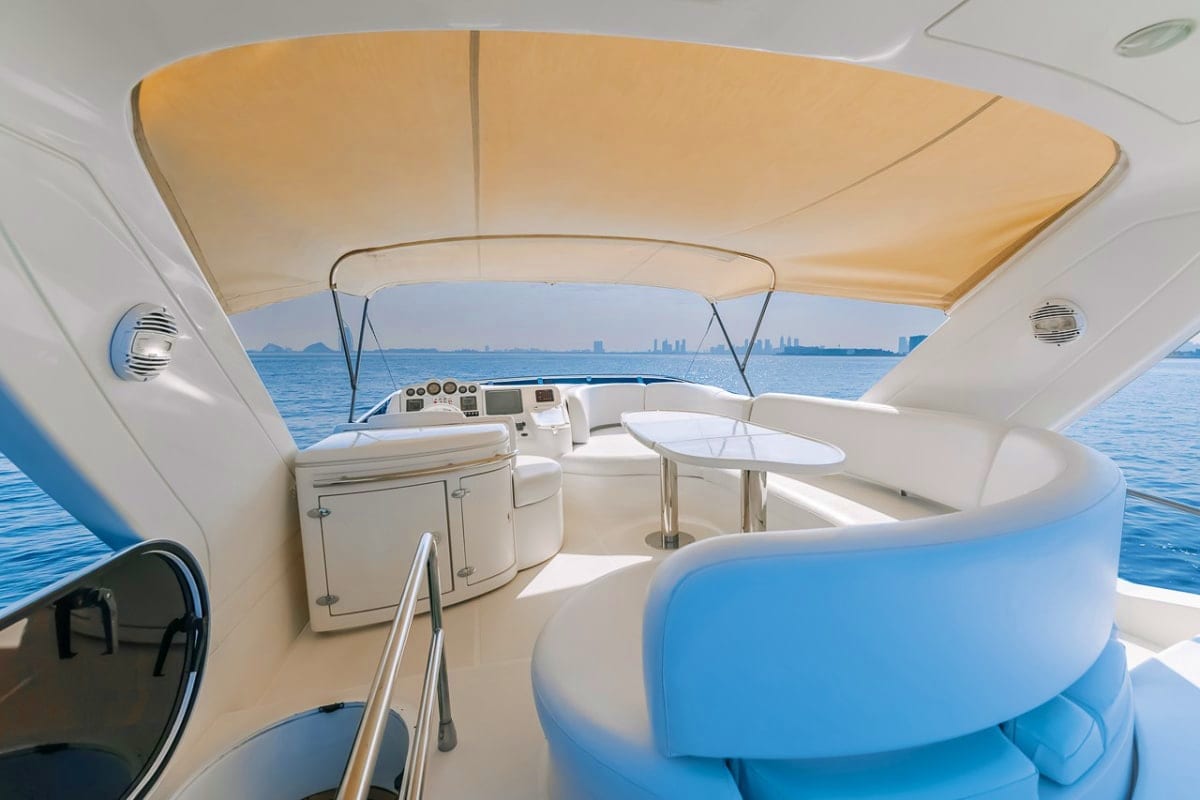 50 Ft Candy Cruise Yacht upper deck with tan canopy, white seating, control console, and coastal city skyline across blue wat