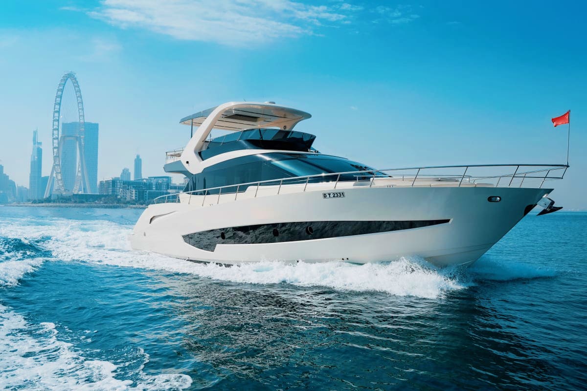 Luxury white and teal motor yacht anchored in shallow coastal waters with London Eye and city skyline visible in background