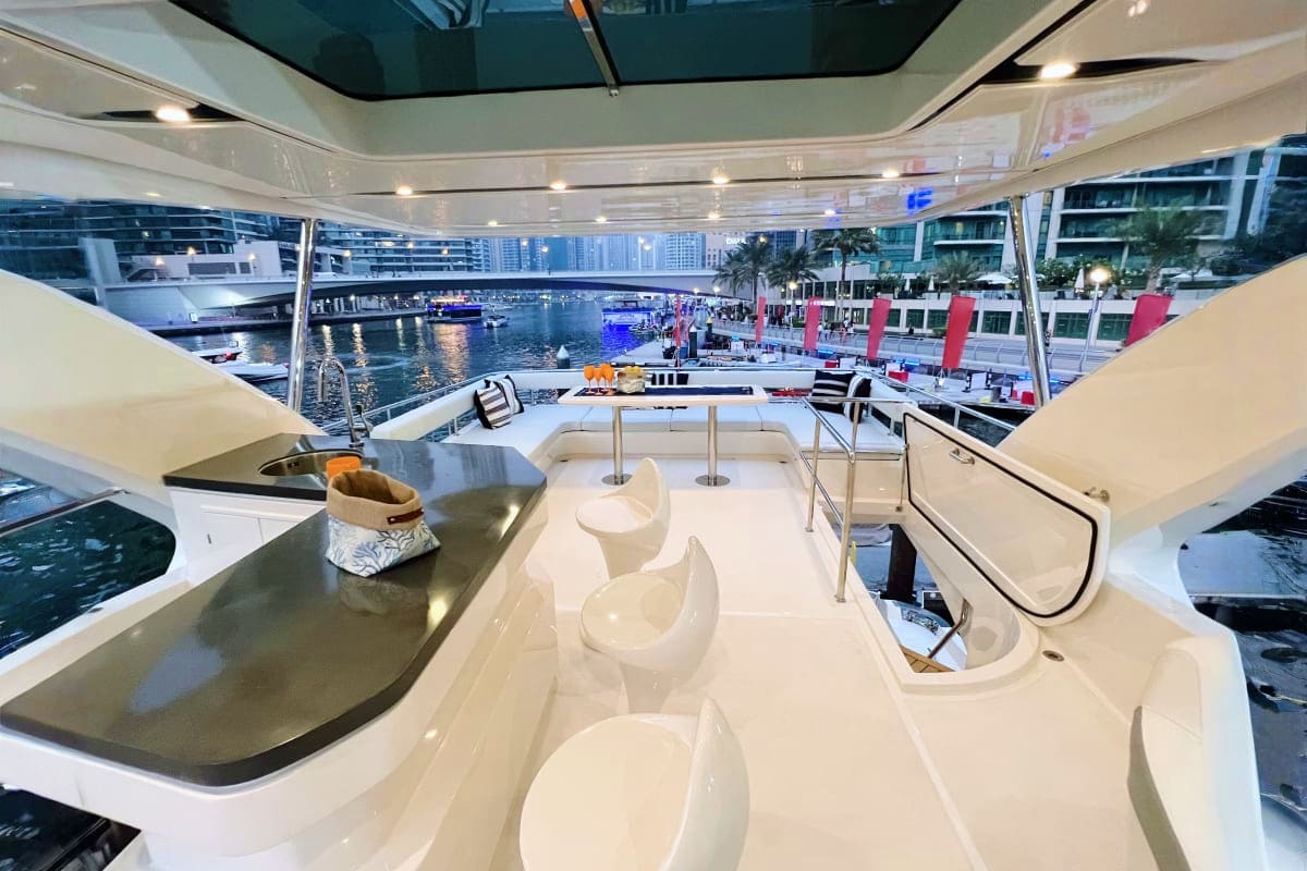 Custom X32 yacht flybridge with white seating, stainless steel countertop, and panoramic water views of marina docked boats a