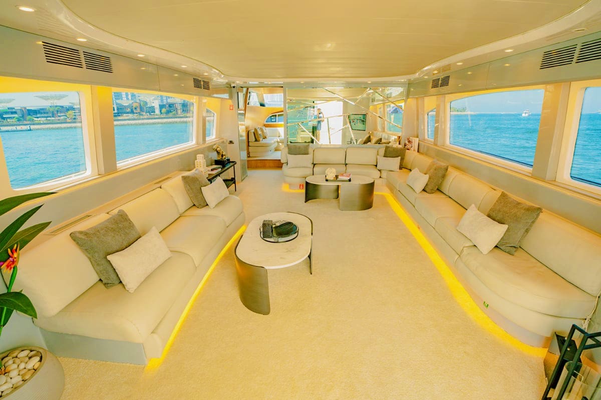 Maiora X12 Maiora X12 luxury yacht main saloon interior with cream seating, yellow accents, and panoramic ocean views through windows
