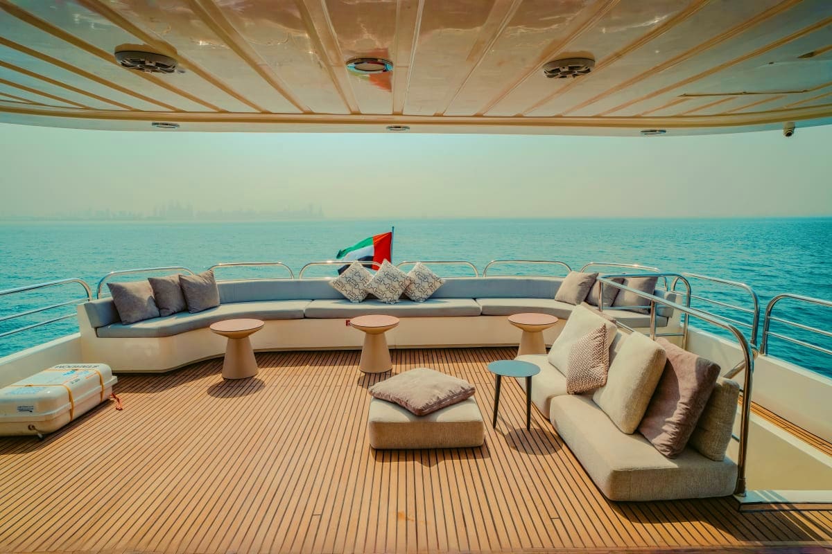 Stardom Luxury yacht Stardom upper deck with curved seating, teak flooring, and turquoise ocean view with distant city skyline