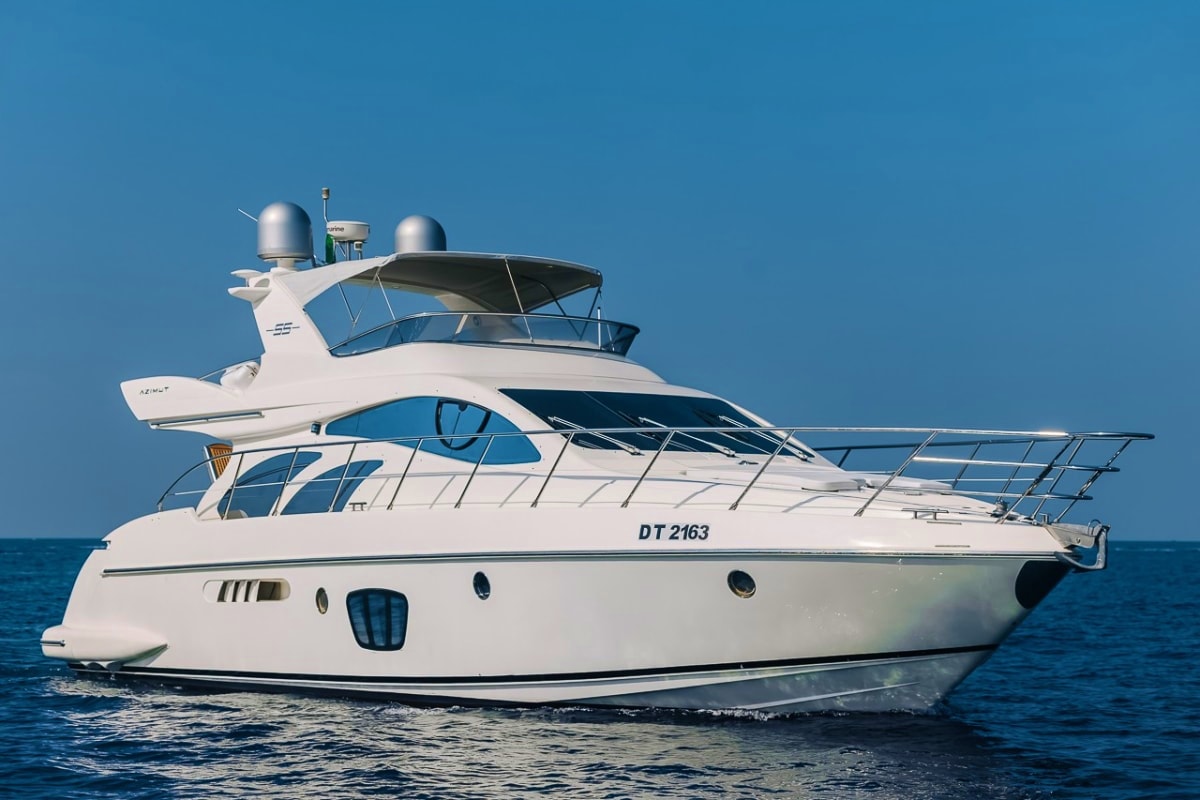 White luxury motor yacht with registration DT 2163 anchored in blue ocean water under clear sky