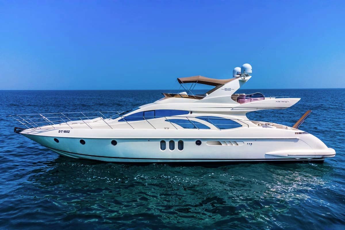 Luxury white 62-foot yacht anchored in clear blue ocean water with canopy top and multiple portholes visible