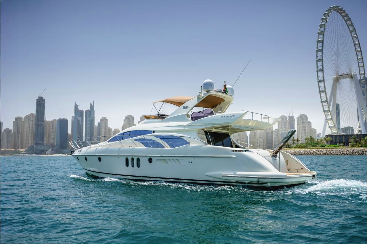 Luxury white motor yacht anchored in clear blue water with Dubai skyline and Ferris wheel in background