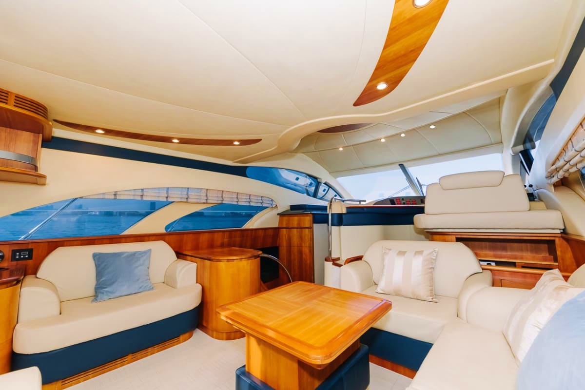 Luxury yacht interior cabin with cream seating, wood furnishings, and large windows overlooking the ocean