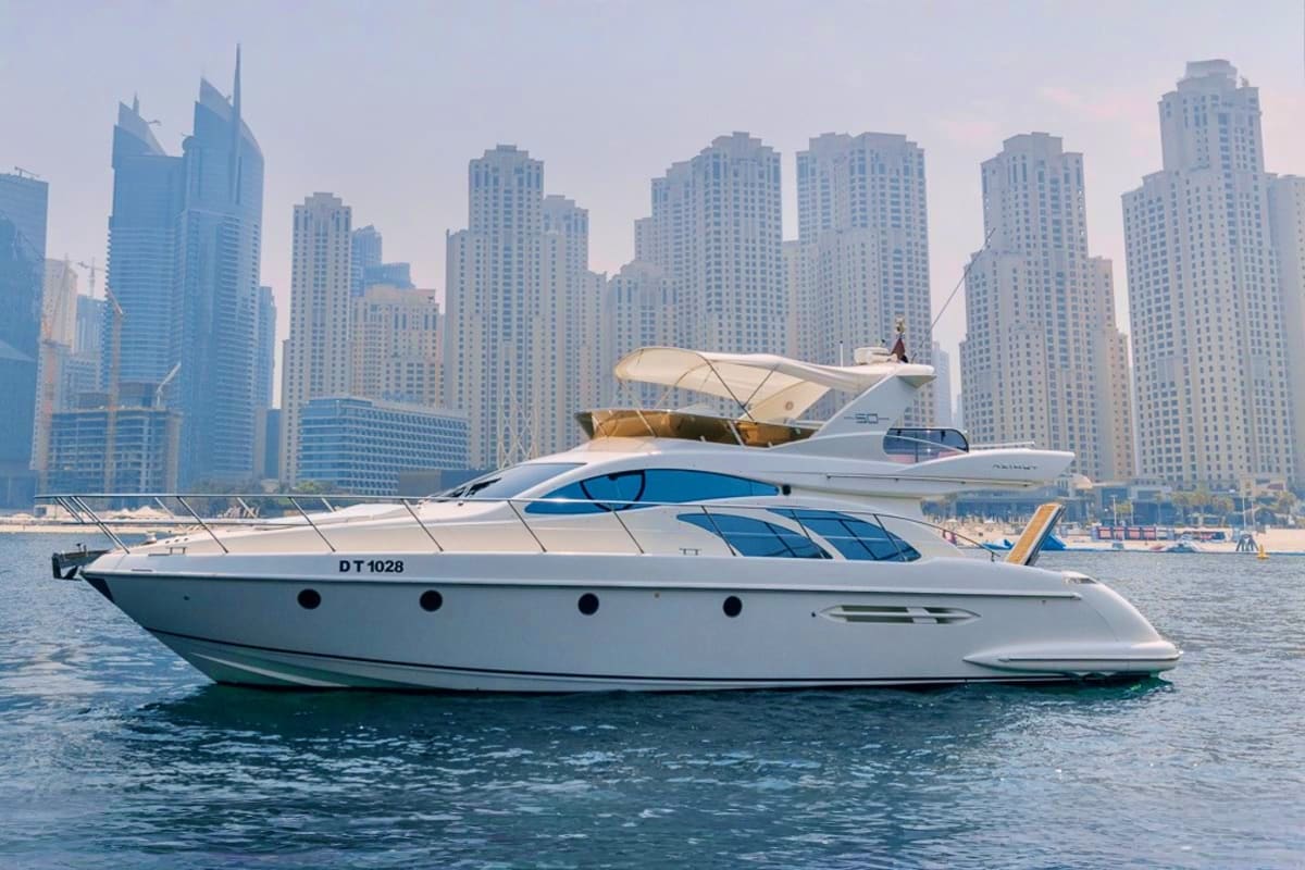 White and blue luxury yacht moored in turquoise water with Dubai Marina high-rise buildings in background