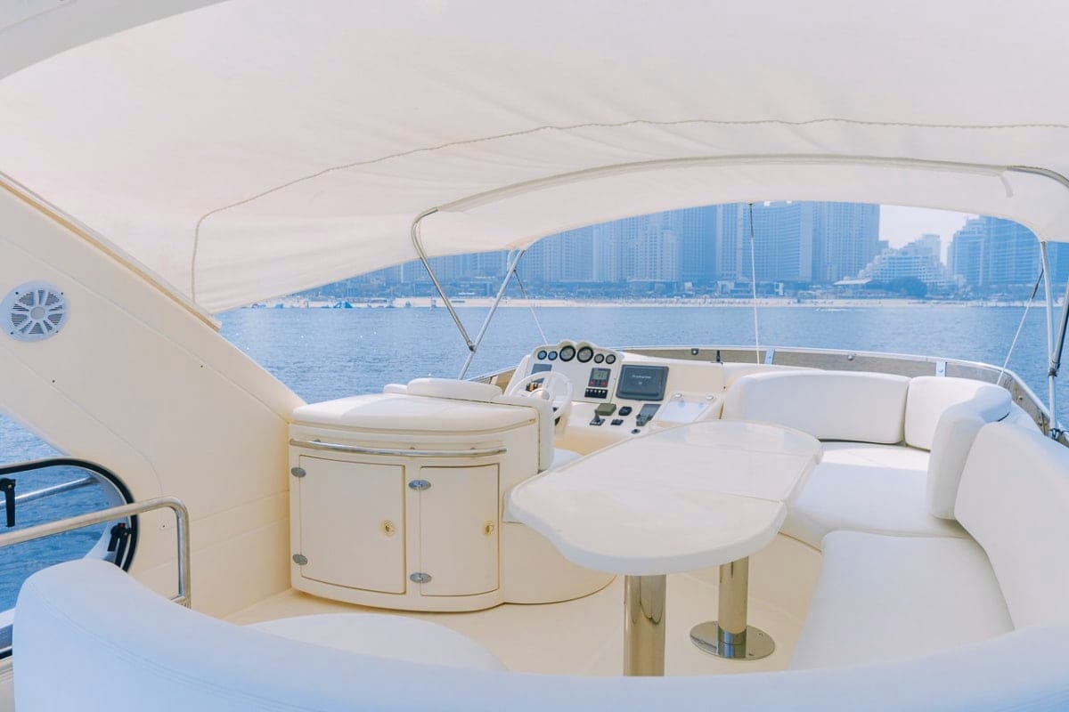 50 Ft Coastal Star Yacht cockpit with white seating, helm station, and coastal city skyline visible across blue water