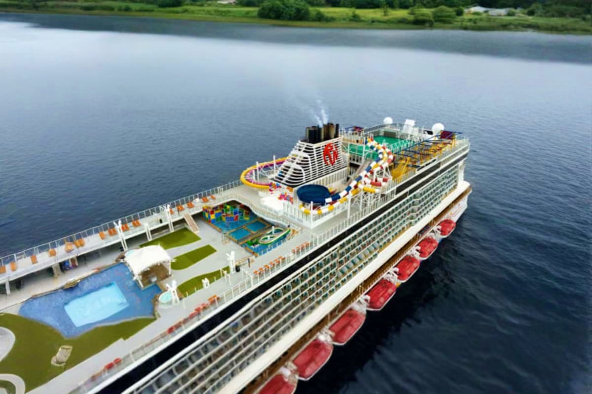 Genting Dream Singapore Roundtrip Cruise Aerial view of Genting Dream cruise ship anchored in calm waters with multiple deck levels, pools, and water slide visible