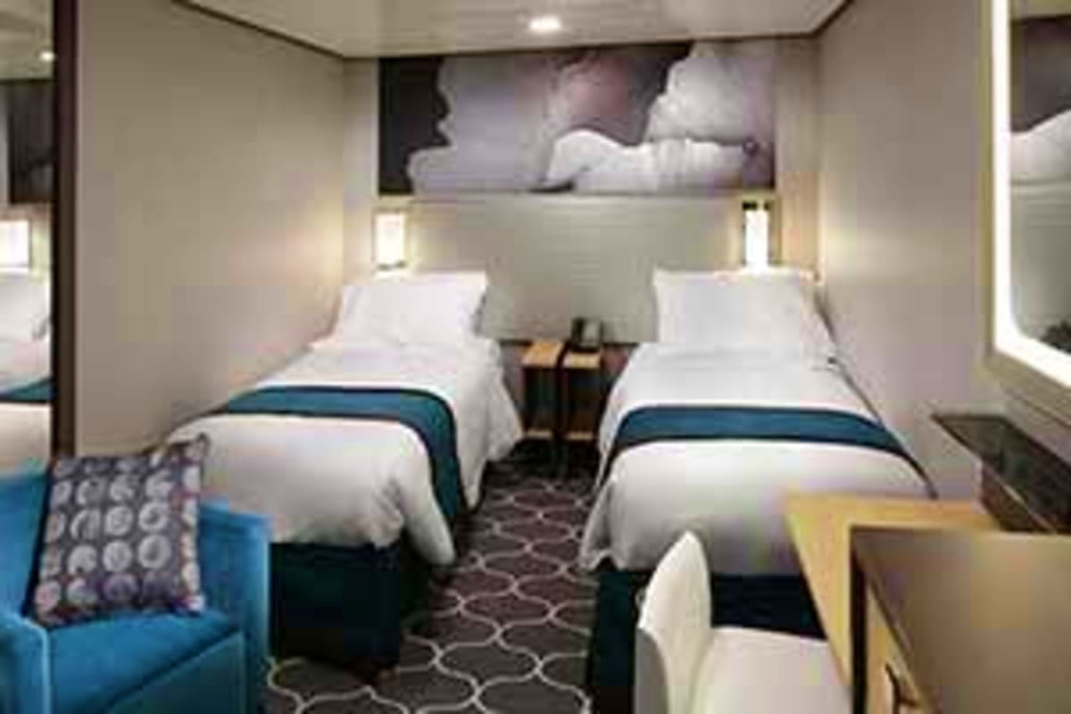 Spectrum of the Seas Vietnam Cruise Modern cruise ship cabin with two twin beds, white bedding with teal accents, small seating area, and porthole window