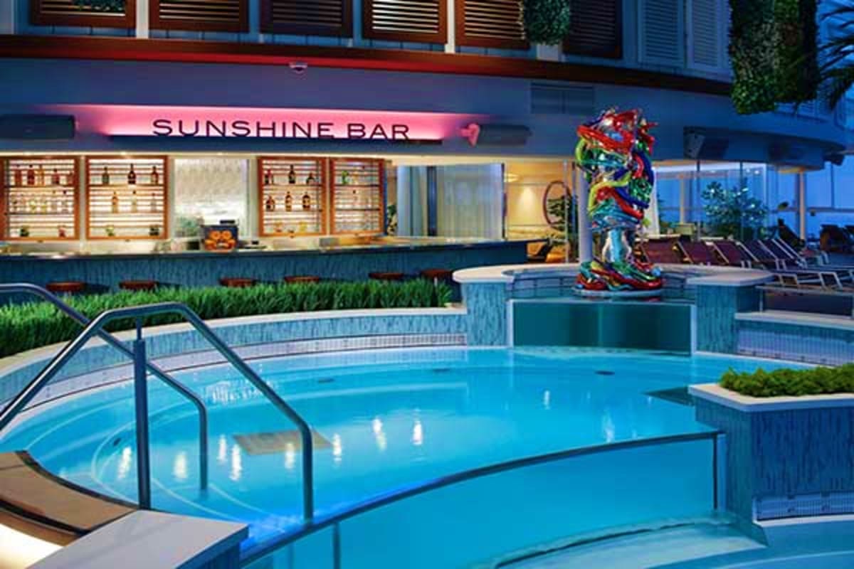 Spectrum of the Seas Asia Cruise Swimming pool area at Sunshine Bar on Spectrum of the Seas cruise ship with lounge chairs and colorful deck sculpture
