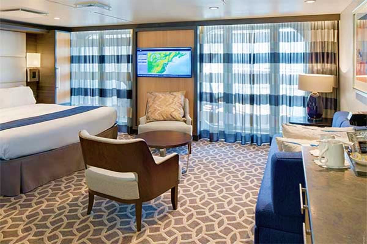 Best of Japan and South Korea Cruise Luxury cruise ship cabin with king bed, seating area, flat-screen TV displaying weather map, and ocean view balcony with stri