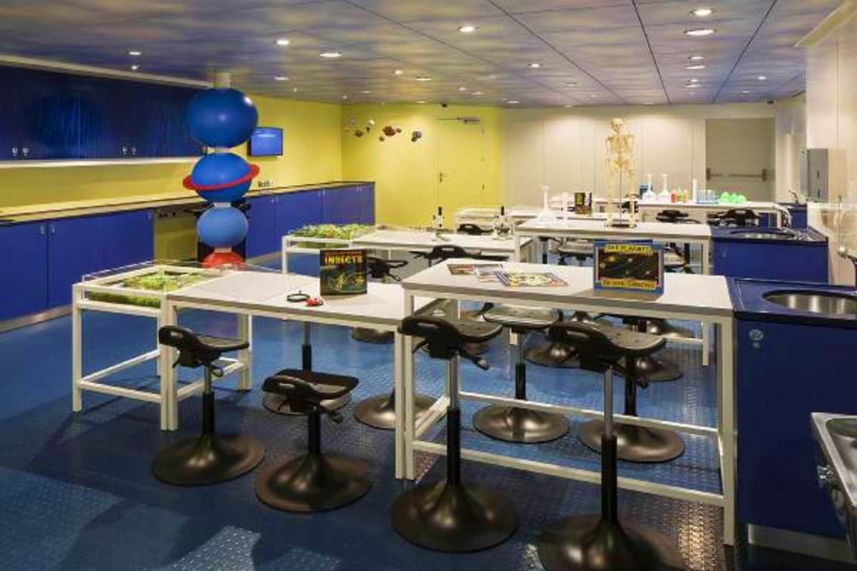 Spectrum of the Seas Japan Cruise Modern children's science-themed classroom with blue and yellow walls, lab tables with black stools, and interactive exhibits