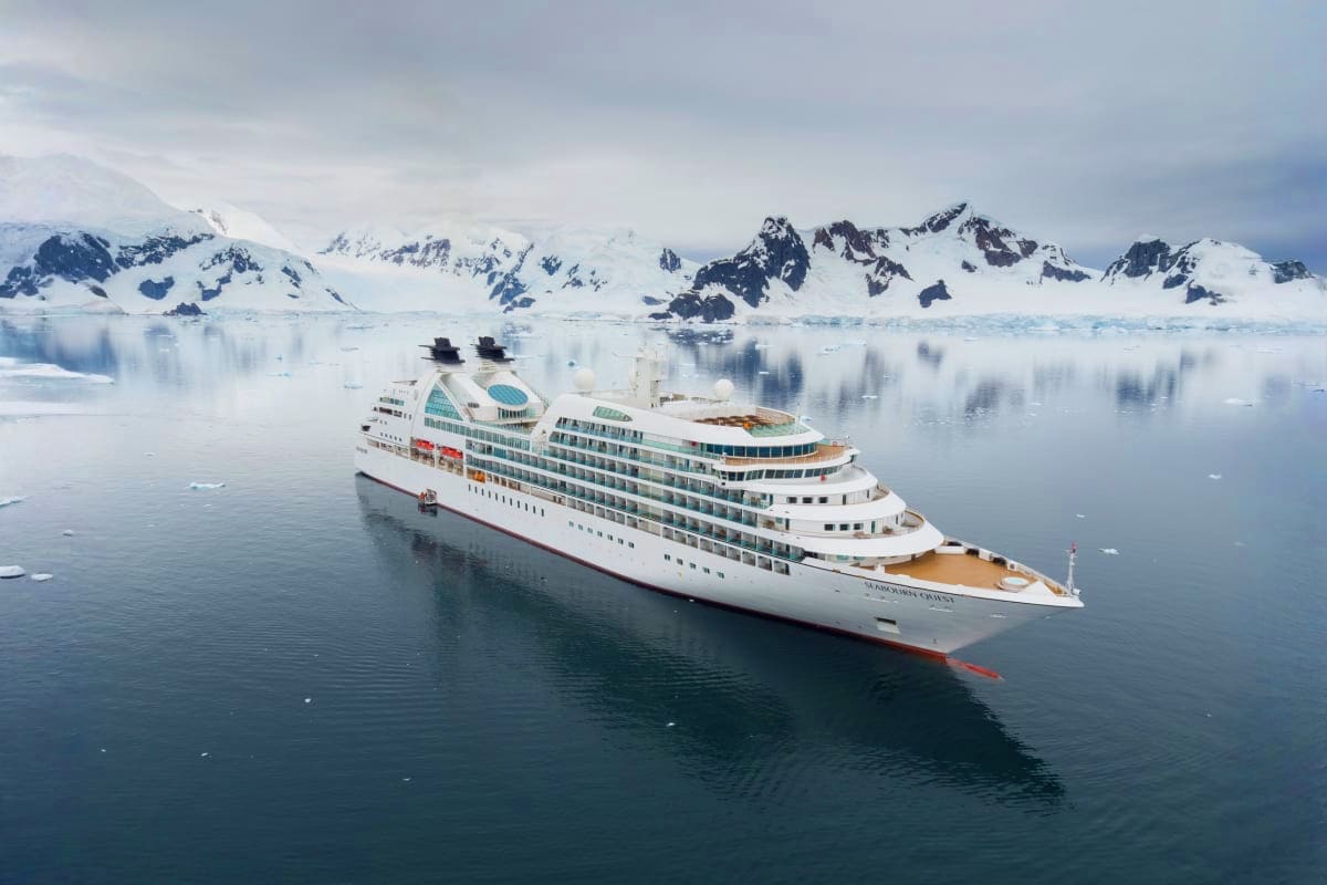 Seabourn Quest Aegean Gems Cruise Large luxury cruise ship anchored in icy Antarctic waters with snow-covered mountains in the background