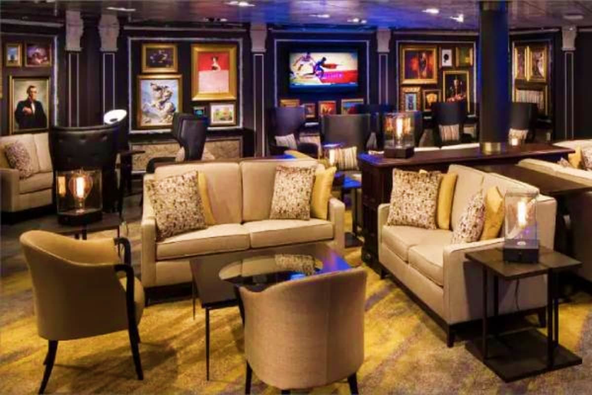 Eurodam Alaskan Explorer Voyage Luxury home theater and lounge area with cream seating, dark wood cabinetry, framed artwork, and flat-screen television on cr