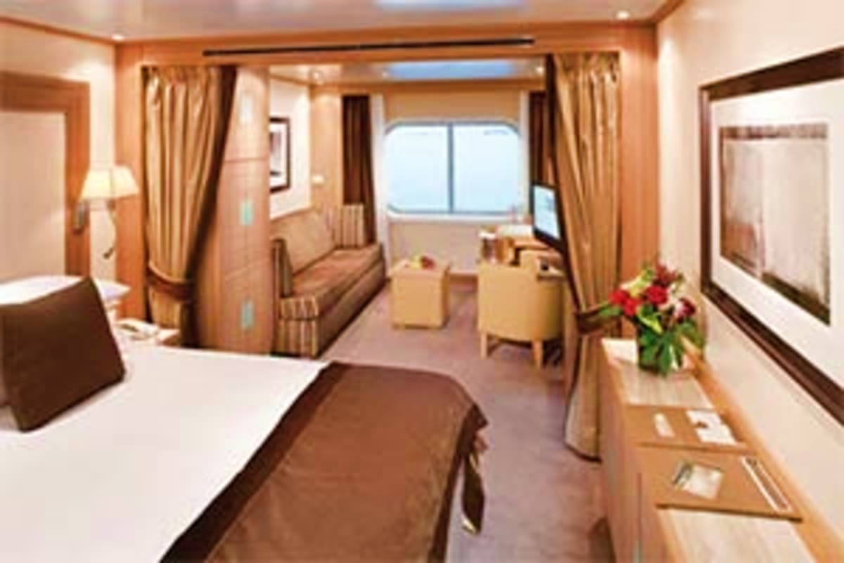 Seabourn Quest Adriatic Greek Treasures Luxury cruise ship cabin interior with queen bed, sitting area, ocean view windows, and elegant wood furnishings