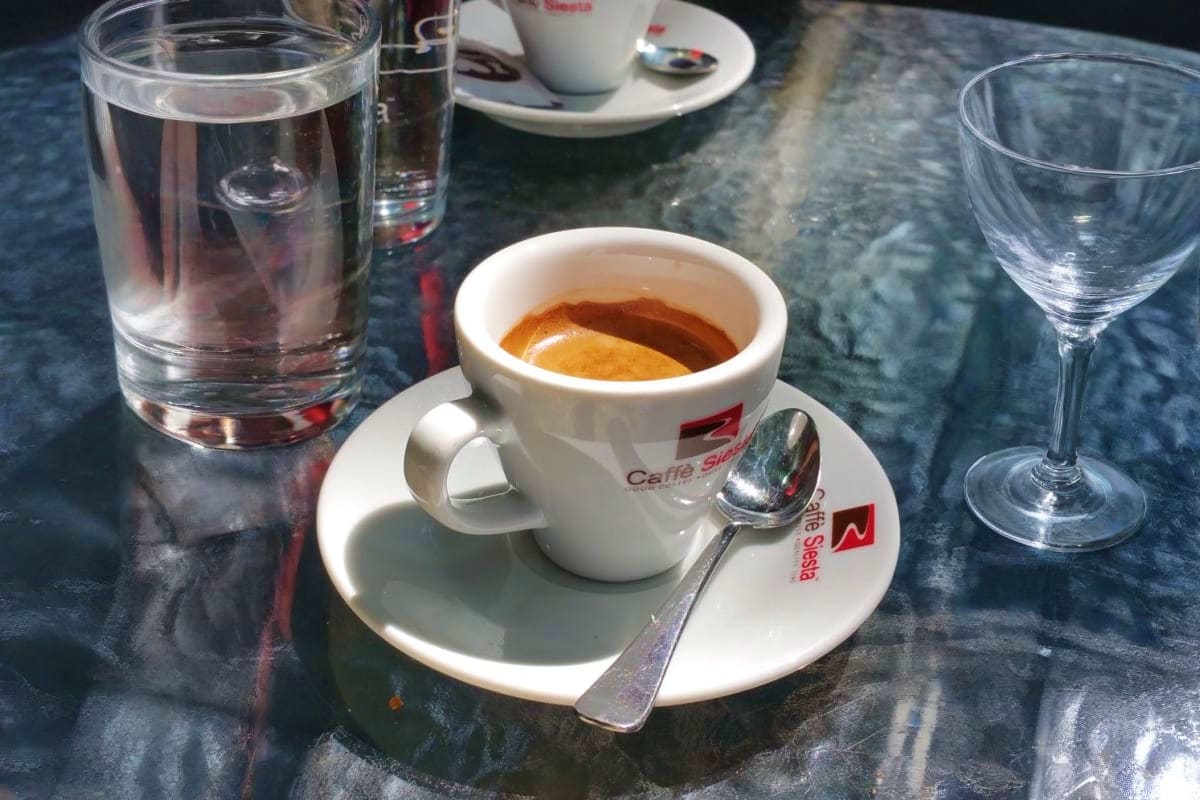 Costa Fascinosa Southern Europe Discovery Espresso coffee served in white branded cup at outdoor café table with water glasses and marble surface