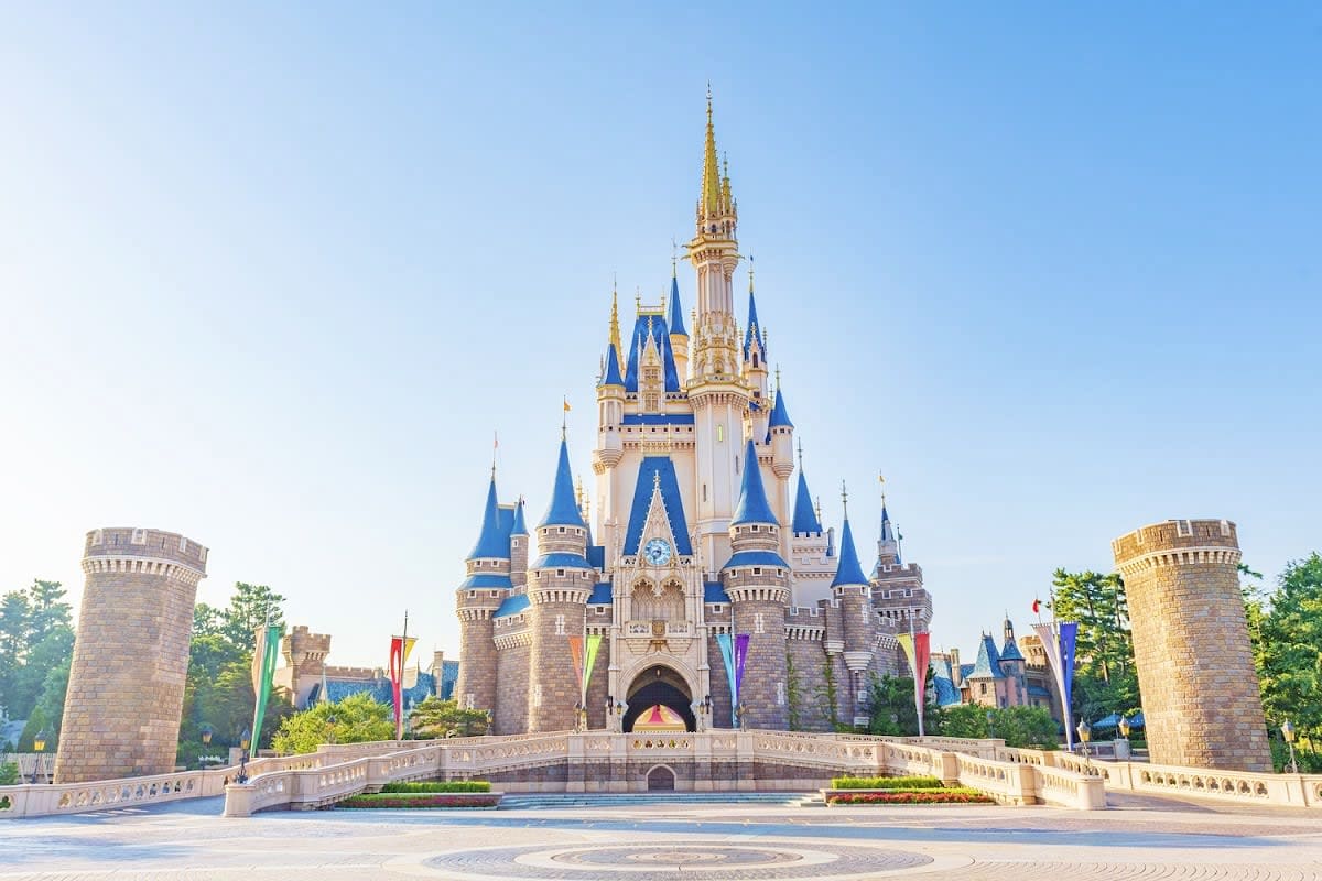 Cinderella Castle at Disney's Magic Kingdom theme park with blue spires, gold accents, and stone towers under clear sky