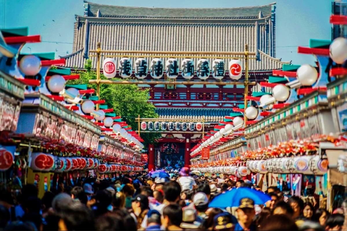Crowded Tokyo street festival at Nakamise shopping arcade with traditional Japanese temple gate, red lanterns, and festive de