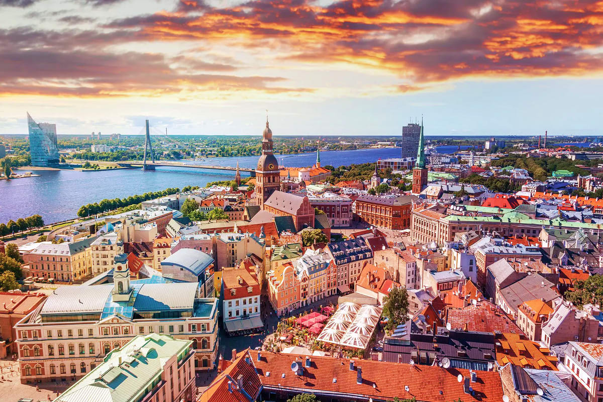 Baltic Capitals Discovery Tour Aerial view of Kiel, Germany at sunset with historic red brick buildings, cathedral spires, sailboat bridge, and waterfront c